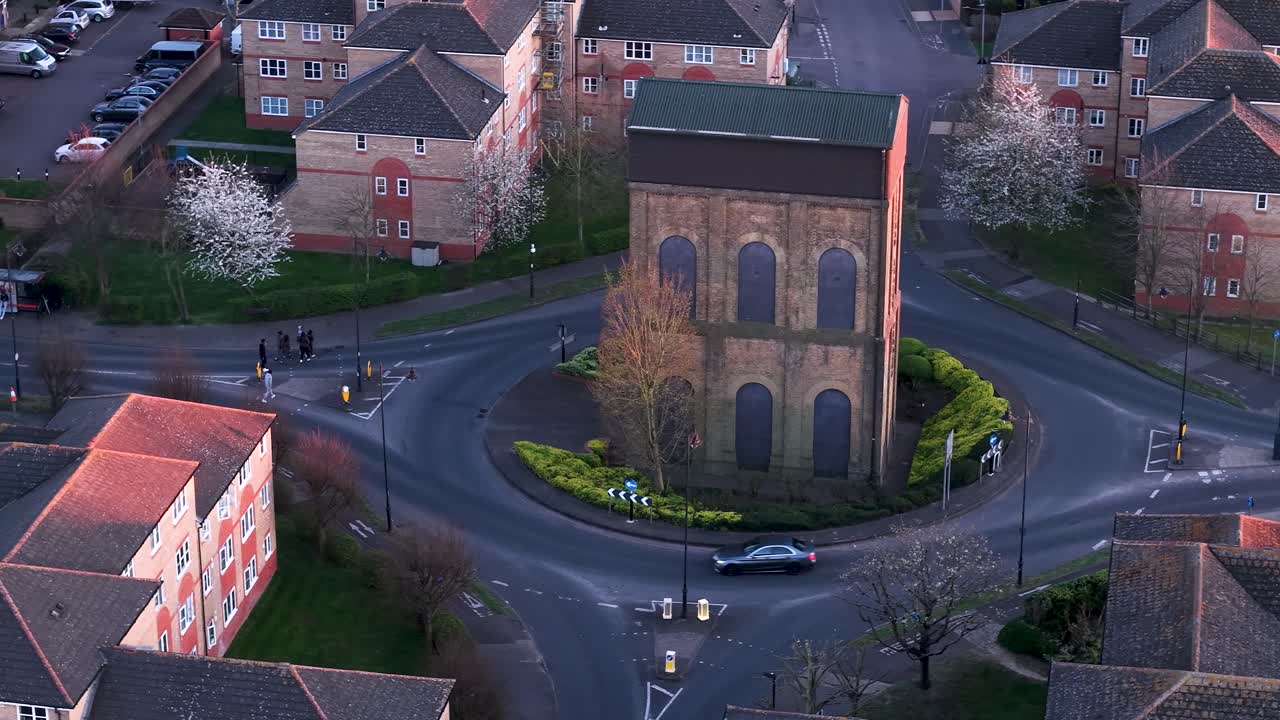 Aerial view circling old water tank tower on Enfield island village roundabout near London city