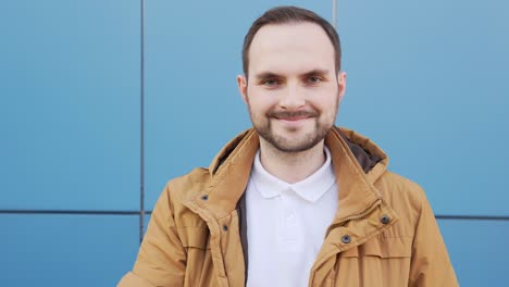 a cheerful smiling bearded man shows a chocolate doughnut to the camera