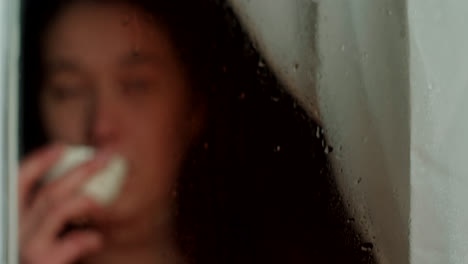 woman drinking coffee by a rainy window