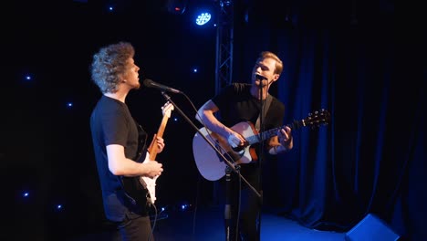 concert rock band performing on stage with two electric guitars singers. music video punk, heavy metal or rock group. slow motion instrument playing band of two men