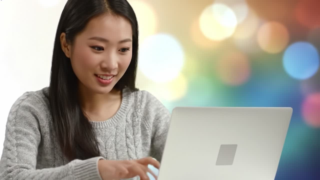 A joyful young woman engages with her laptop in a vibrant setting, showcasing her enthusiasm and focus while using technology in a light-filled environment