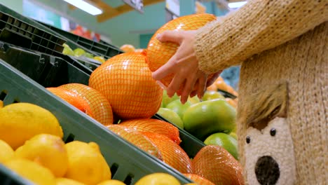 mujer comprando frutas cítricas exóticas frescas en la tienda de comestibles
