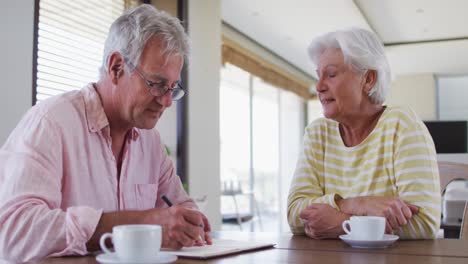 senior caucasian couple with talking to each other discussing finances together at home