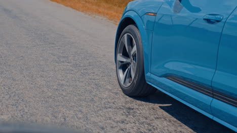 close-up view on the side part of a car and a wheel at moving the road. wheel of luxury car turning slowly on asphalt road.