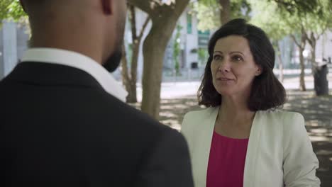 cheerful businesswoman talking with colleague outdoor.