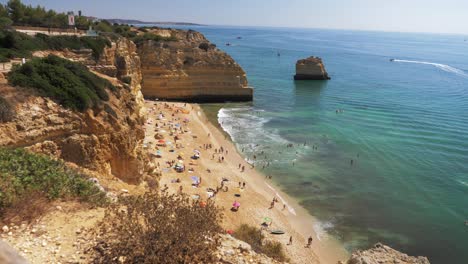 cámara lenta de la playa de marinha y el mar azul en portugal con turistas relajándose en la playa durante el clima soleado
