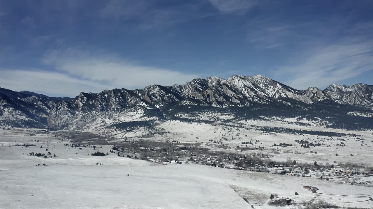 Vista aérea con paneo para mostrar las montañas nevadas de Boulder, Colorado.