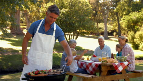 Happy-man-doing-barbecue-for-his-family-and-smiling-at-camera