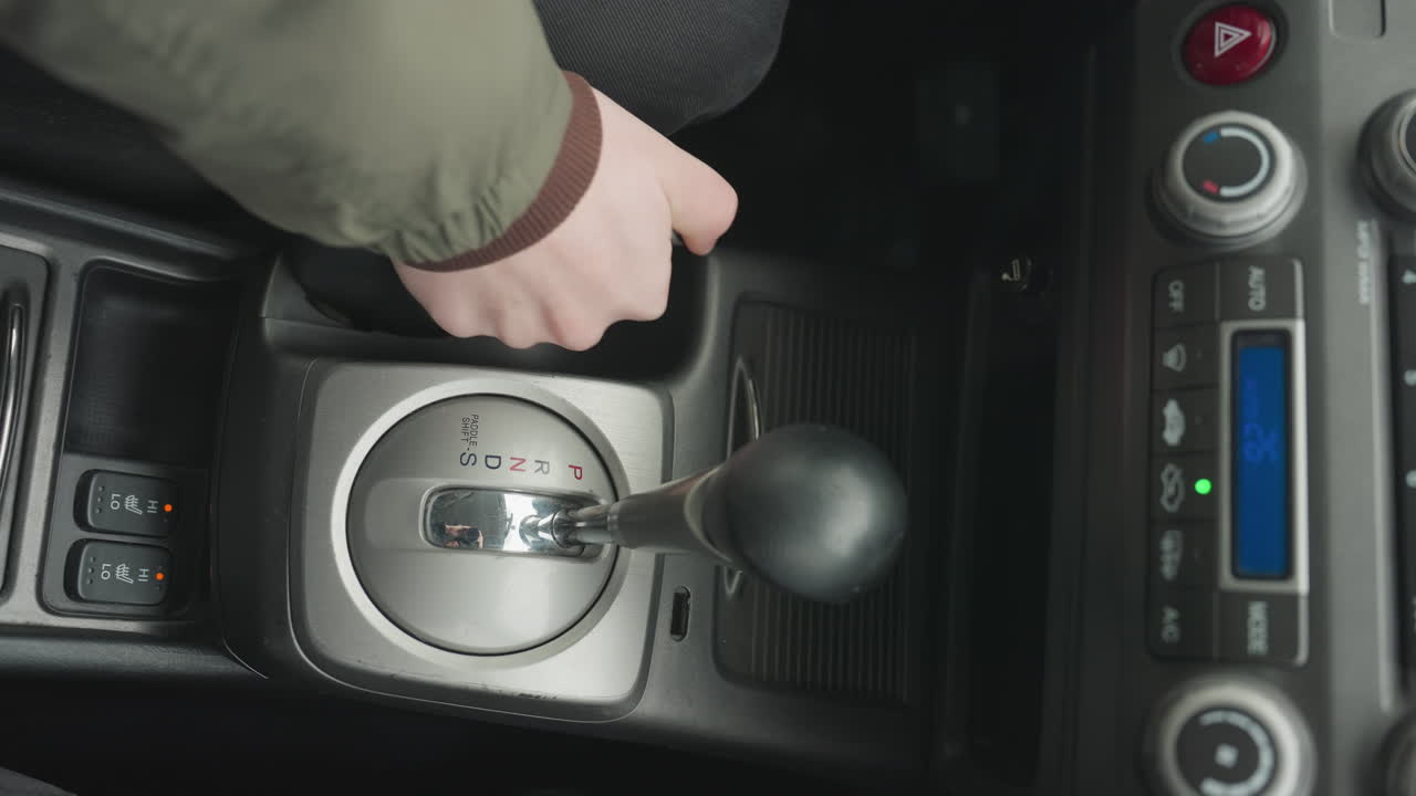top down view of driver pulling down hand brake lever then shifting gear lever into neutral position on center console inside vehicle cabin under daylight safe parking routine with close detail
