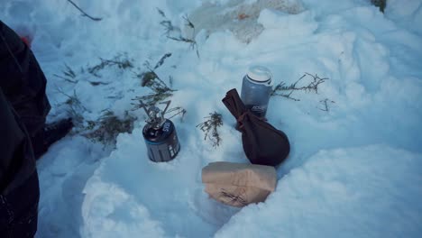 Person,-Die-Eine-Aluminium-Kaffeemaschine-In-Einen-Tragbaren-Kochherd-Einsetzt---Wintercamping-Im-Freien---Hochwinkelaufnahme