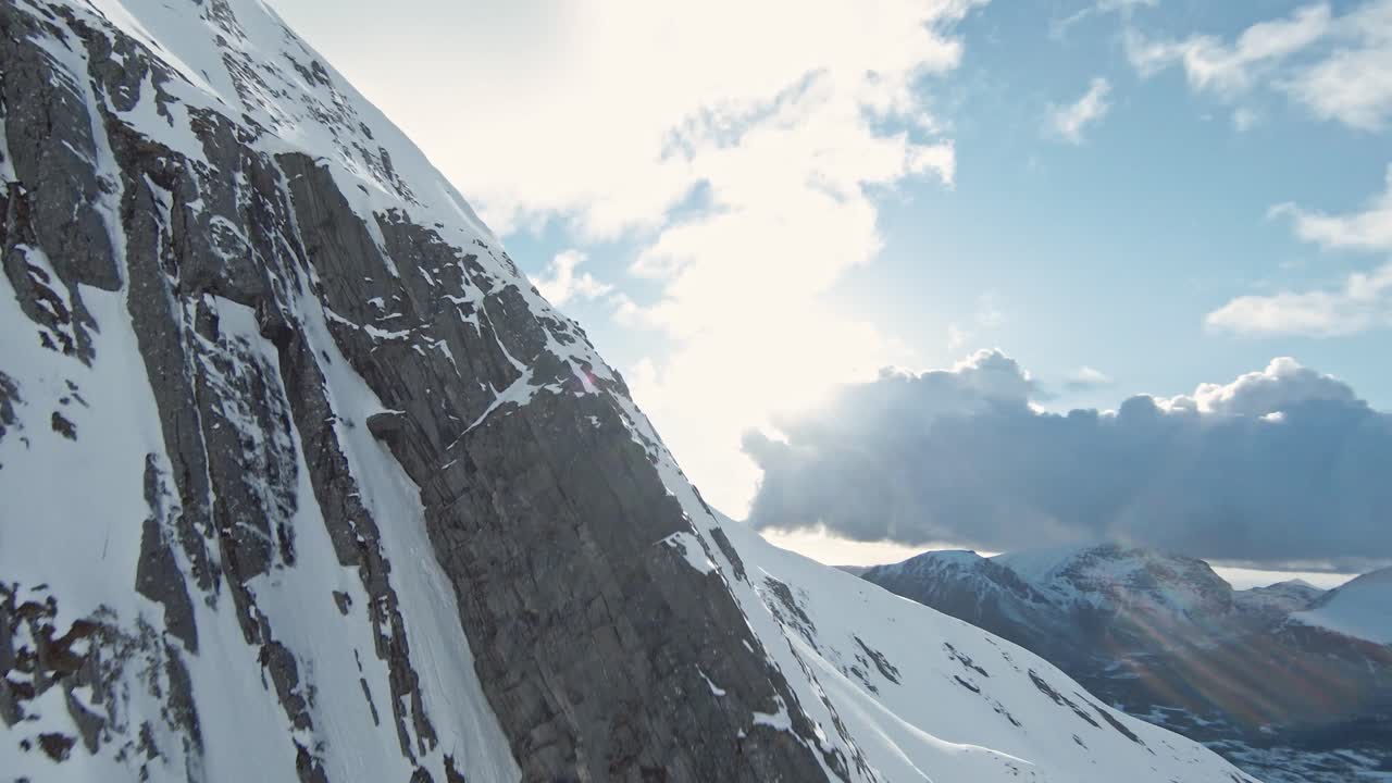 fpv 무인 항공기를 비행하는 동안 얼음 산 경사면 능선 뒤에 햇빛이 드러납니다.