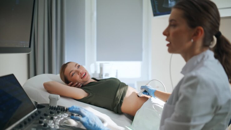 Primo piano di una donna che si sottopone a un'ecografia in una clinica per la gravidanza. Futura mamma che parla con il ginecologo