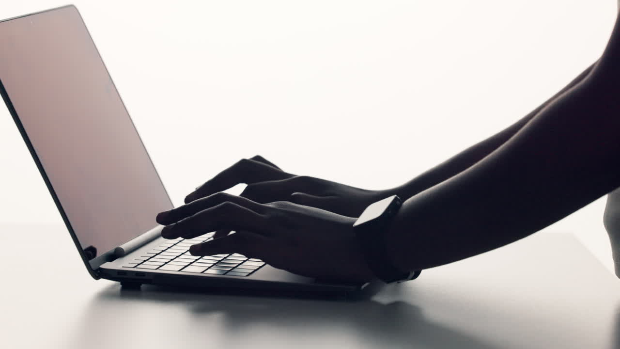 Silhouette of hands typing on a laptop