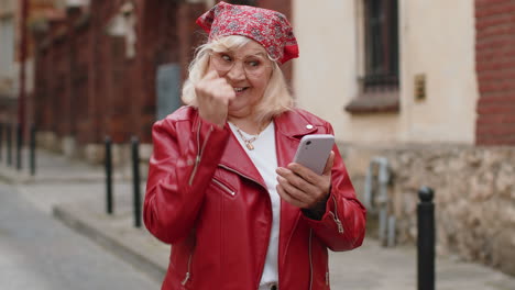 Ältere-Frau-Nutzt-Ihr-Mobiles-Smartphone-Und-Feiert-Den-Gewinn-Einer-Guten-Nachrichtennachricht-Im-Freien-In-Der-Stadtstraße