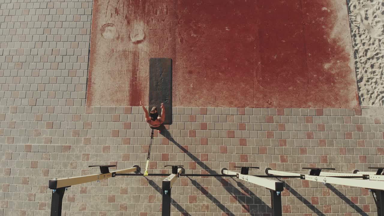 야외 운동. 서스펜션 스트. 에어로  뷰. 운동적인 젊은 여성은 루프 로프를 사용하여 전신 저항 운동을 하고 있습니다. 도시 야외 스포츠 경기장, 체육관. 야외 피트니스 훈련. 건강한 라이프 스타일 개념. 아침 스포츠 훈련.