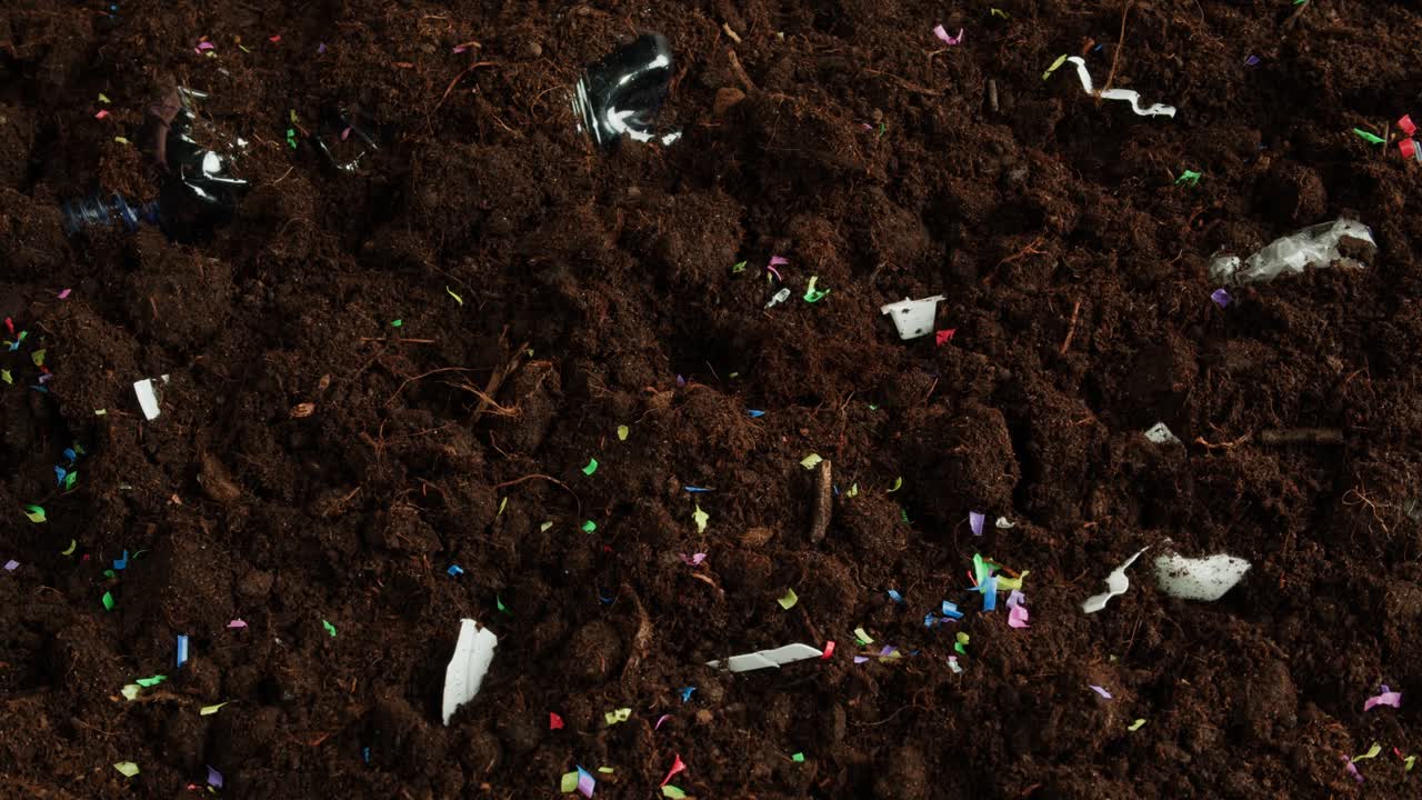 Hand removing trash from soil