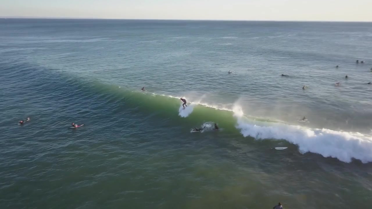 Dronekuva surffaajasta ratsastamassa ja kääntymässä suurella sinisellä valtameren aallolla. Surffauselämäntyyli ja extreme-urheilu Portugalissa.