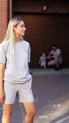 family moment captured outside a home. a woman stands confidently by her home as a child and man enjoy a casual family day in the background