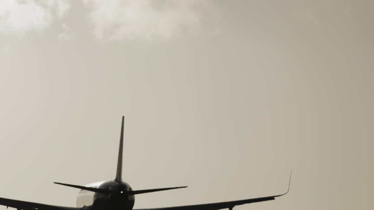 공항에 착륙하기 위해 석양 아래에서 매우 느린 속도로 머리 위를 날아가는 비행기