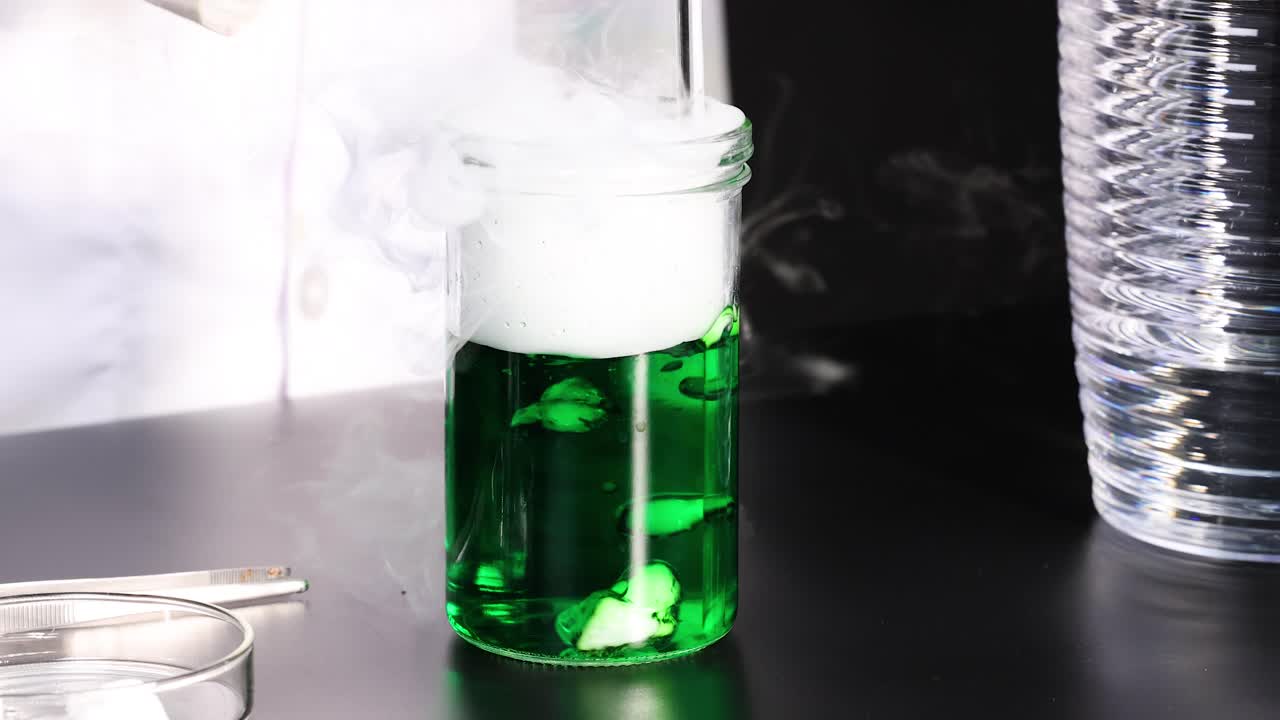 녹색 액체가 반응하여 연기와 거품을 생성합니다.