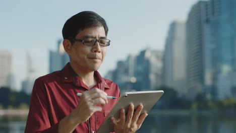man using tablet in a city park