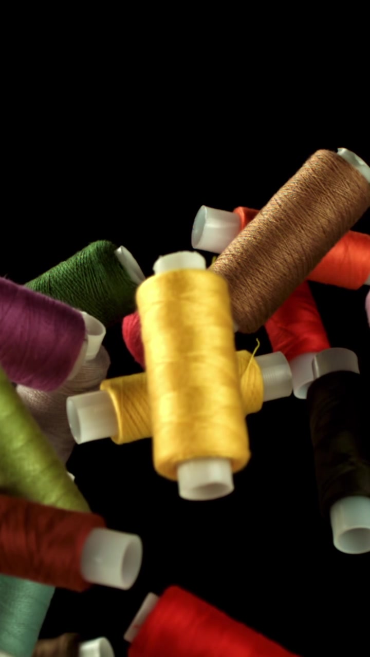 Colorful Spools of Sewing Thread Moving on a Black Background