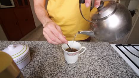 hombre vertiendo agua caliente en una taza para hacer café instantáneo