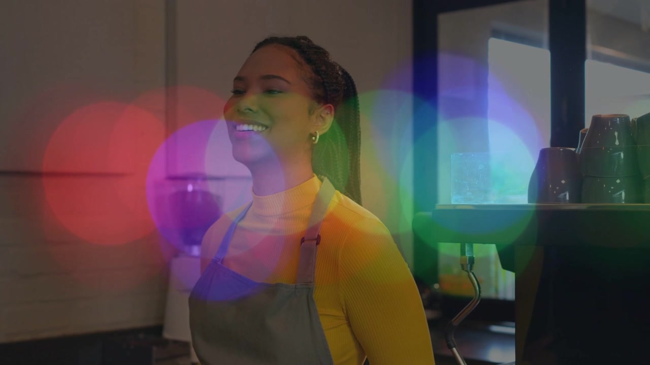 Barista tapping tablet and lifting card at cafe, processing sale, smiling as color flares revealing