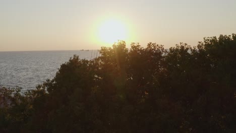 Aerial---Reveal-of-Thessaloniki's-seaside-walkway-and-umbrellas-landmark-with-people-walking-at-sunset