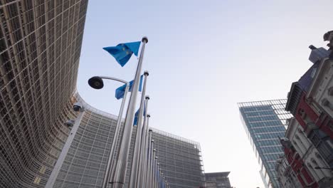 Wide-skyline-view-of-European-Flags-dancing-in-the-wind-against-the-European-Union-headquarters-in-Brussels,-Belgium