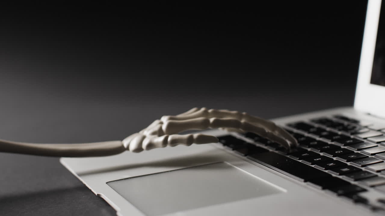 video de primer plano del esqueleto de halloween usando una computadora portátil sobre un fondo negro