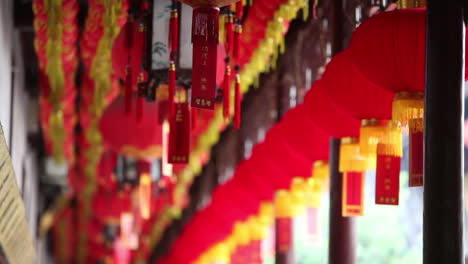 lanterns and tassels hang from the rafters in a buddhist temple in china