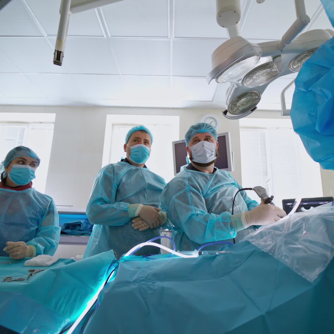 Operation for crushing stones. Medical workers in blue uniform and masks conduct a surgery in modern operating room in clinic.