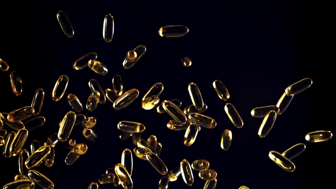 Capsule dorate di Omega 3 che cadono al rallentatore su uno sfondo scuro