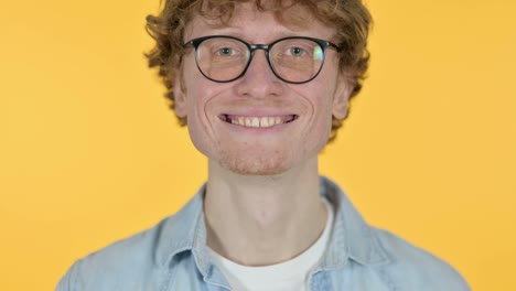 primer plano de un joven pelirrojo sonriente sobre un fondo amarillo