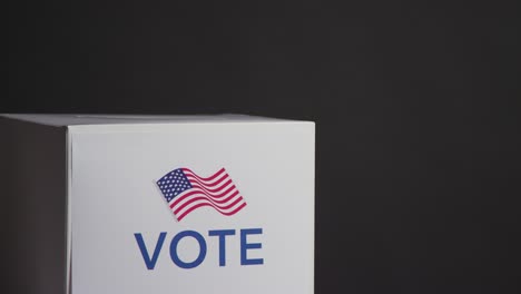 Ballot-Box-With-USA-Flag-In-American-Election-Against-Black-Background