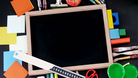 blank slate surrounded by various school supplies