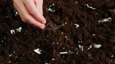 hand picking trash from soil