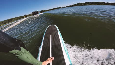 surfer on longboard in wave behind boat