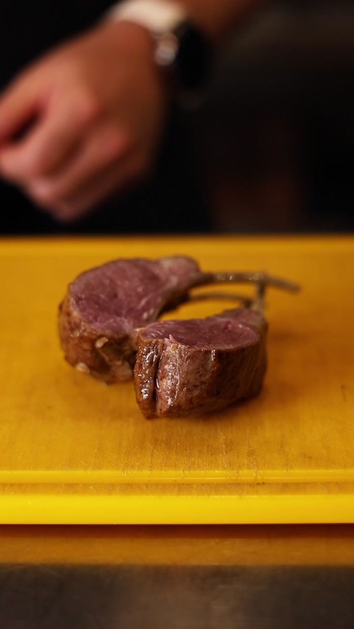 Costolette d'agnello cotte appoggiate su un tagliere giallo