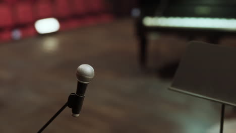 a microphone on a stand in front of a piano in a music studio