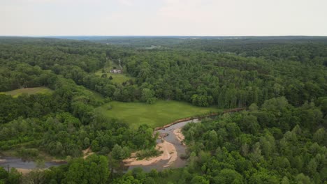 aerial orbit shot of plush green countryside, and a drying creek bed