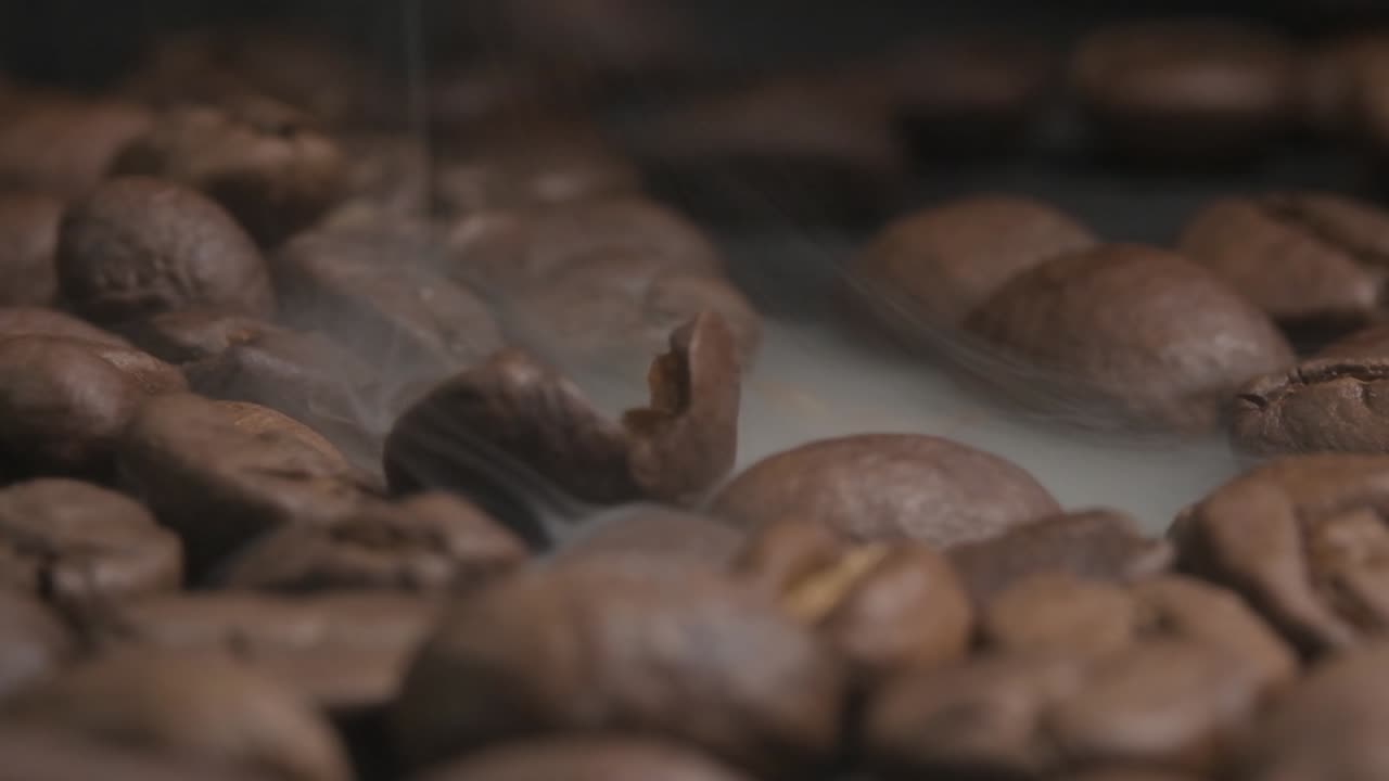 Close up macro shot of a cracked coffee bean, smoke coming from the roasting beans which accelerates a chemical reaction to give coffee its aroma and flavour