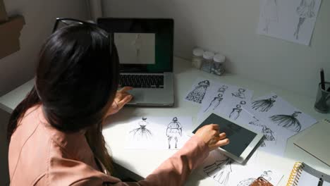 Fashion-designer-working-on-sketches-of-dress-at-design-studio-4k