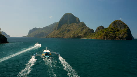 Aerial-speedboat-crossing-outrigger-boat-in-El-nido,-Palawan,-Philippines