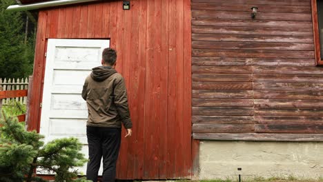 el hombre que sale cierra la puerta blanca de la casa de madera