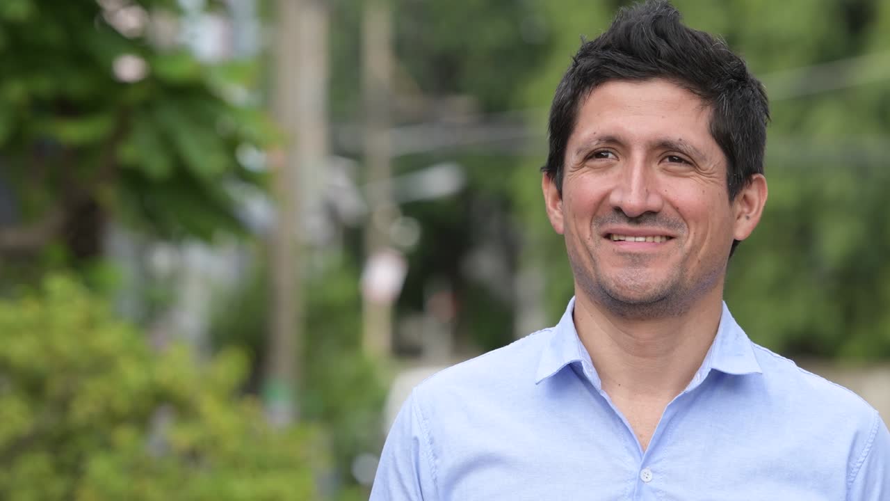 Hispanic businessman smiling while thinking outdoors