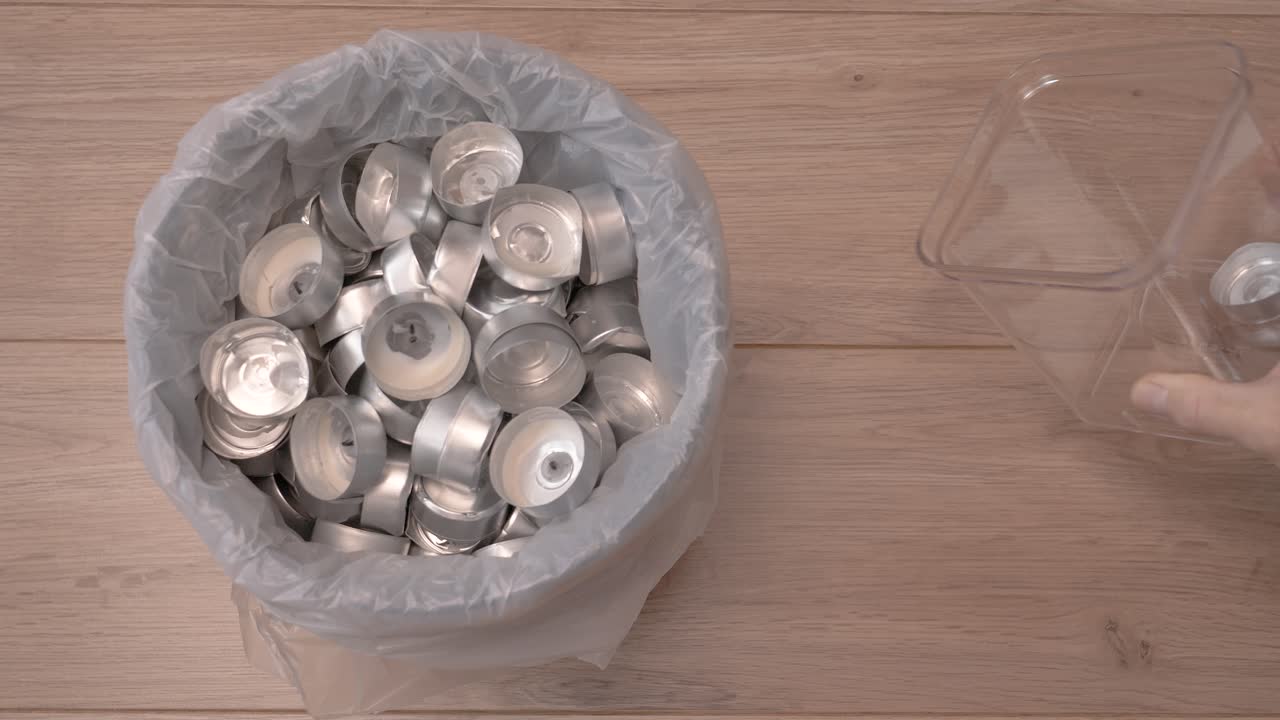 한 남자 가 컨테이너 에서 불 컵 을 재활용 하기 위해 쓰레기통 에 던진다