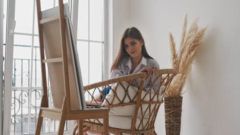 Coquettish-woman-rests-leaning-on-armchair-in-studio