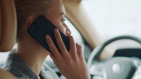 vista traseira de mulher usando telefone atrás do volante. menina chamando smartphone